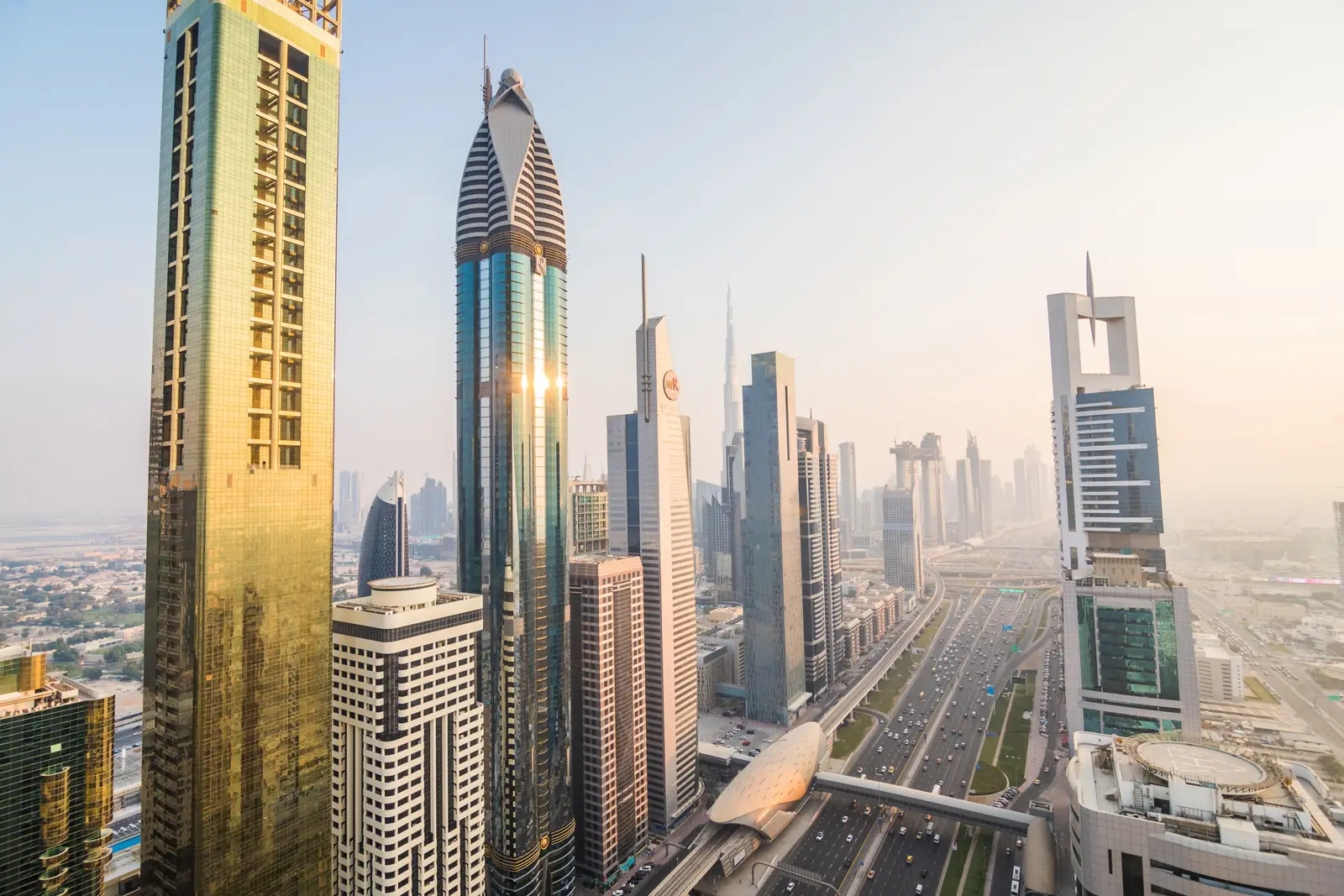 A city skyline of tall glass towers in the Gulf in warm evening light